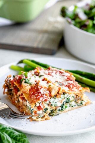 Slice of easy baked vegetable lasagna on a circular white plate.
