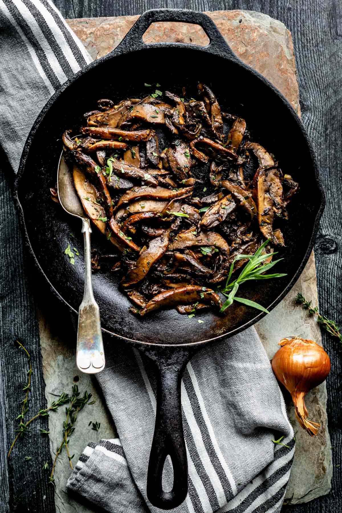 top view of Sautéed portobello mushrooms in a black skillet with a spoon.
