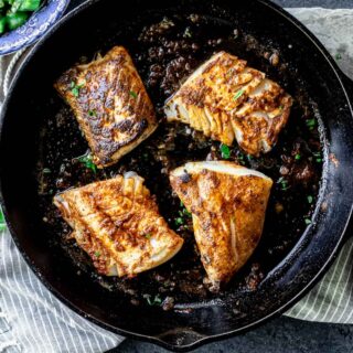 blackened cod fish cooking in cast iron skillet