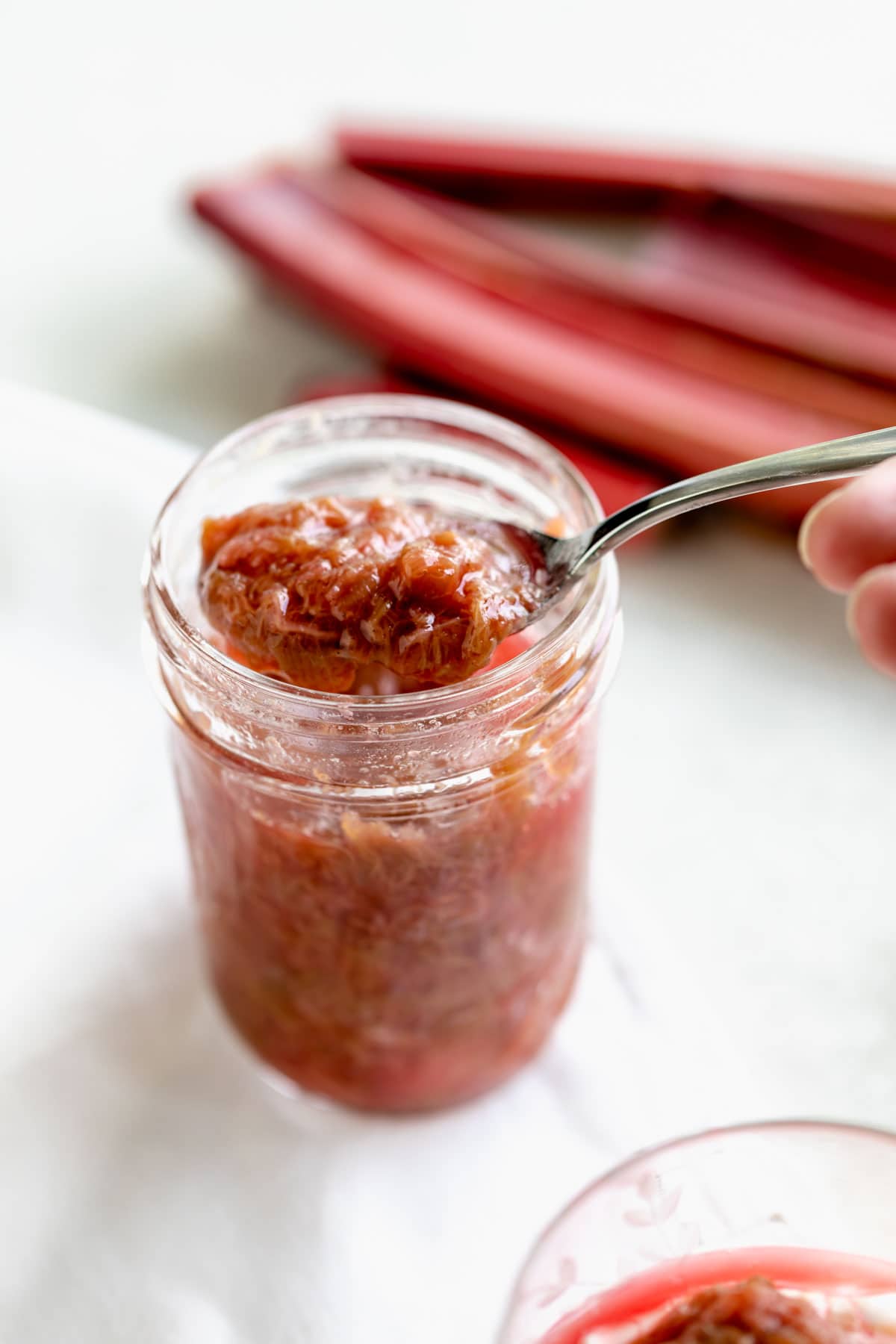 rhubarb compote in a jar with a spoon taking a scoop out