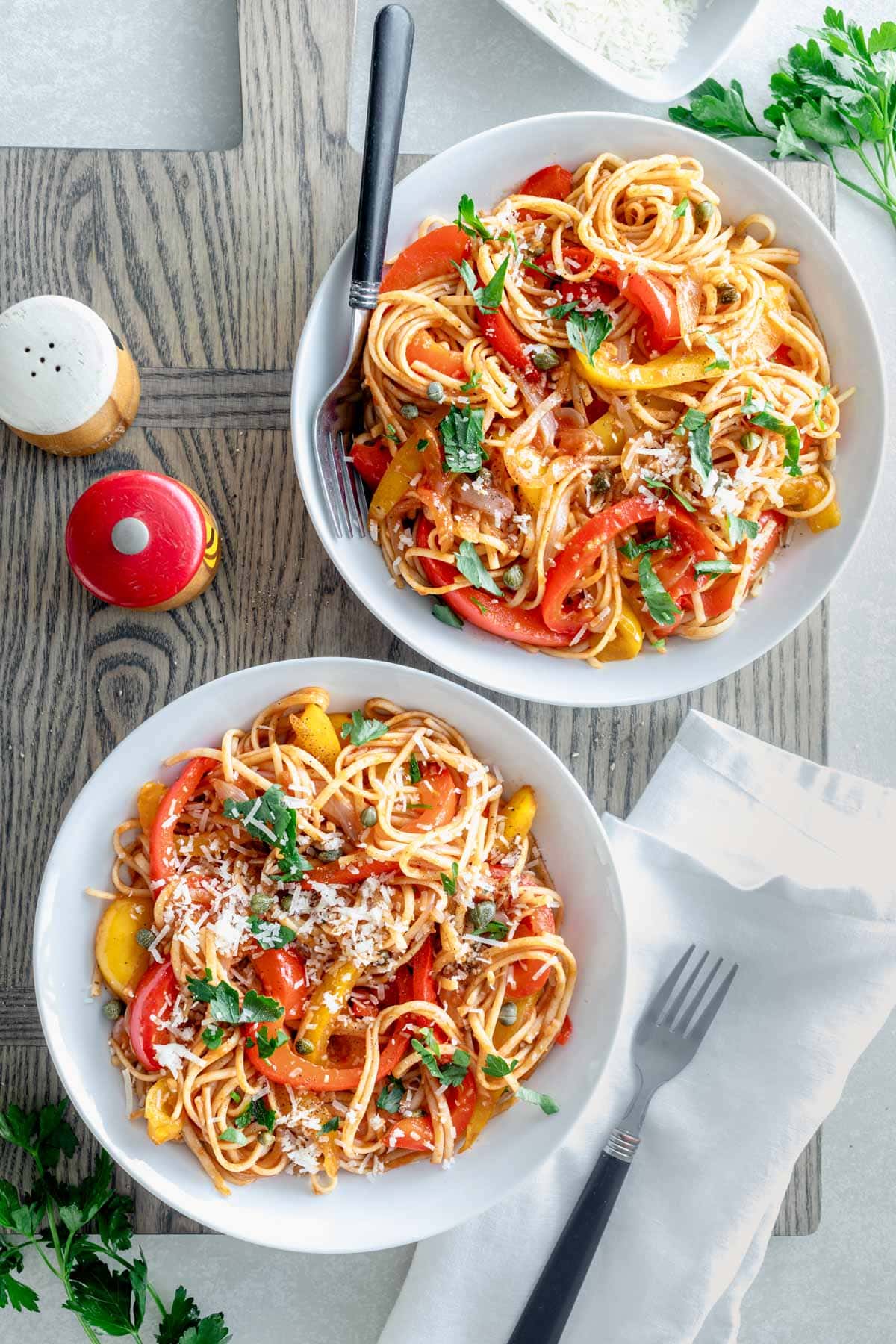 two bowls of easy pasta peperonata sprinkled with parmesan and garnished with parsley