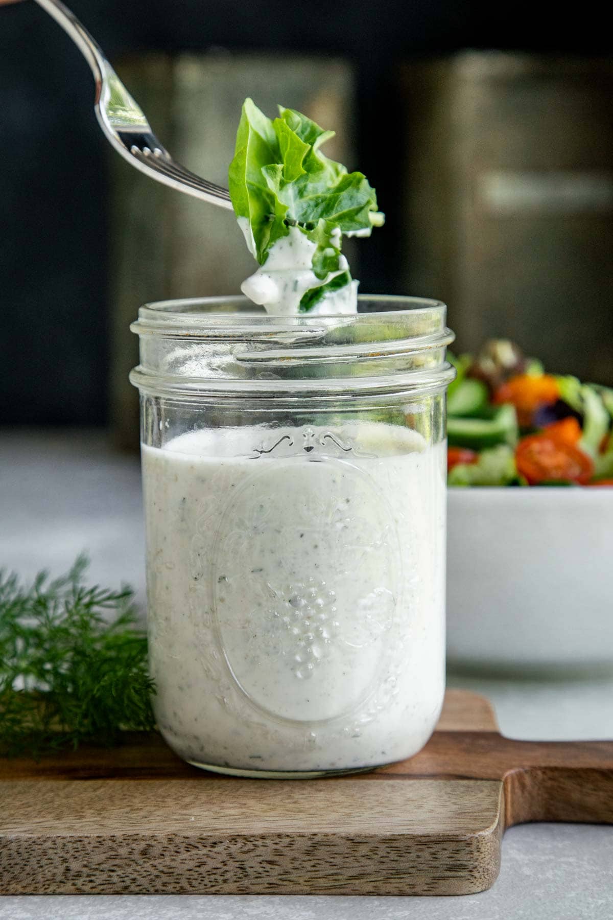 a fork dipping lettuce into a jar of ranch
