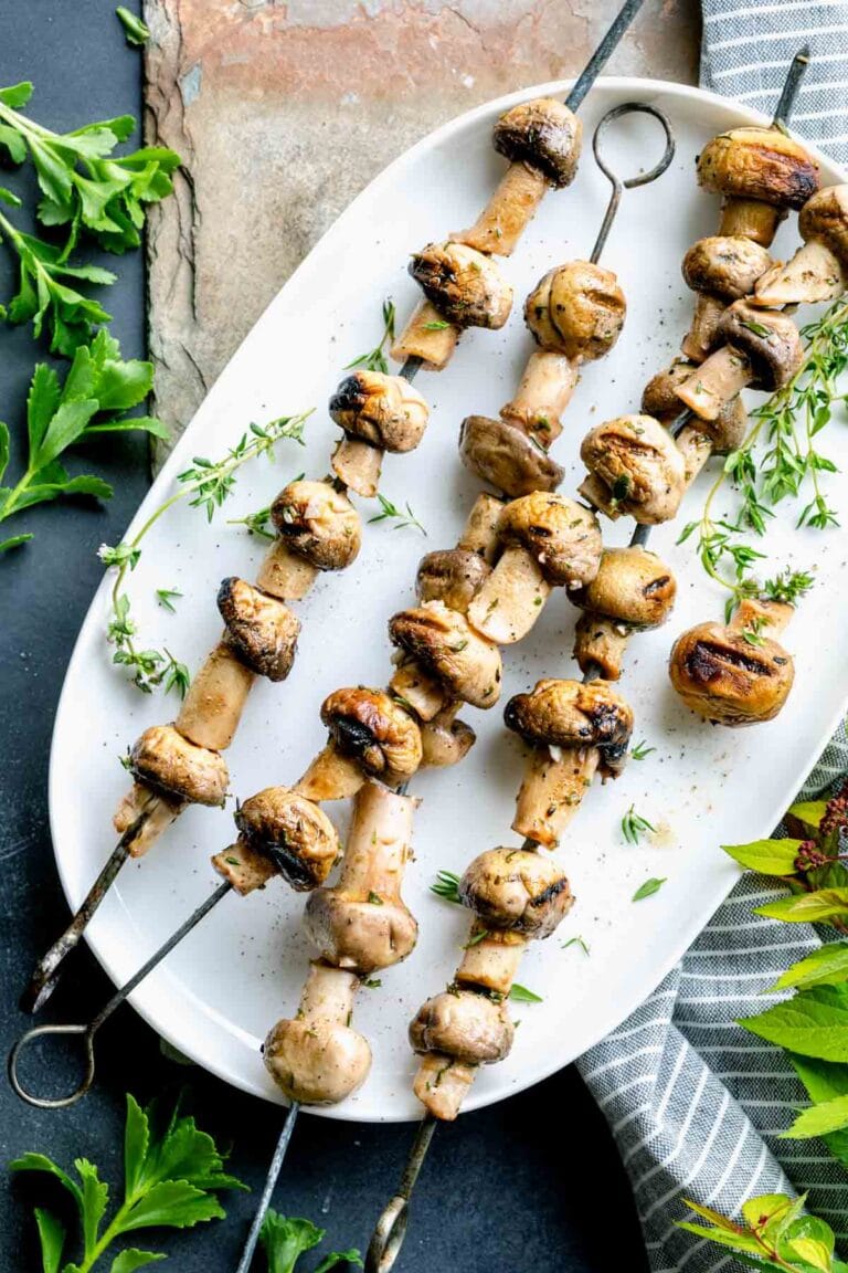 skewered grilled mushroom kebabs on a white platter