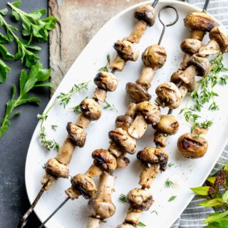 skewered grilled mushroom kebabs on a white platter