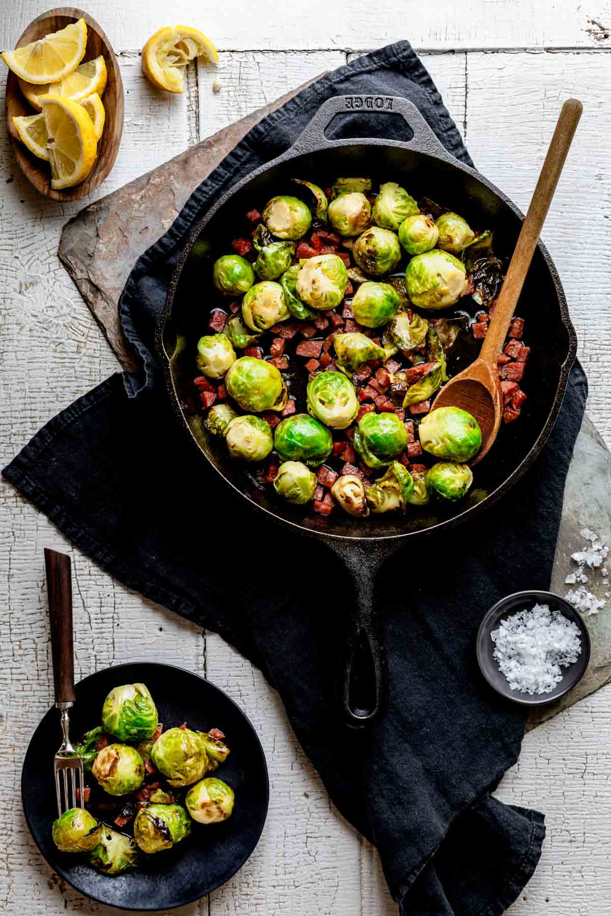 overhead tablescape with skillet with the brussels in it and a small black dish with a serving on it