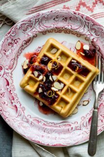 a waffle with cranberry syrup on a red and white plate