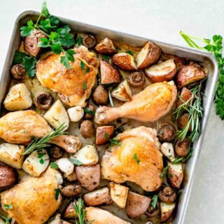 Baked chicken thighs and potatoes on baking sheet