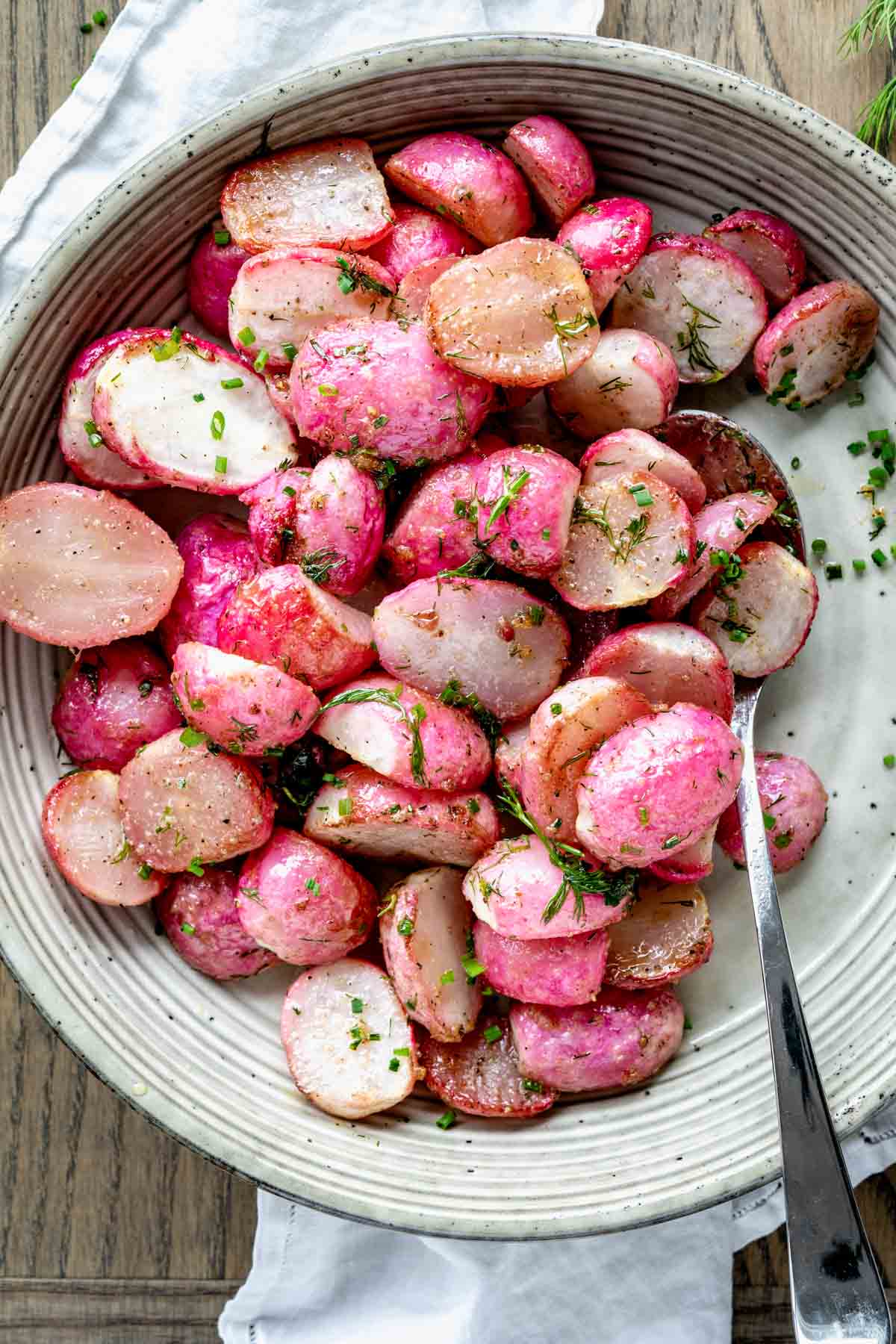 roasted radishes in circular white dish with spoon