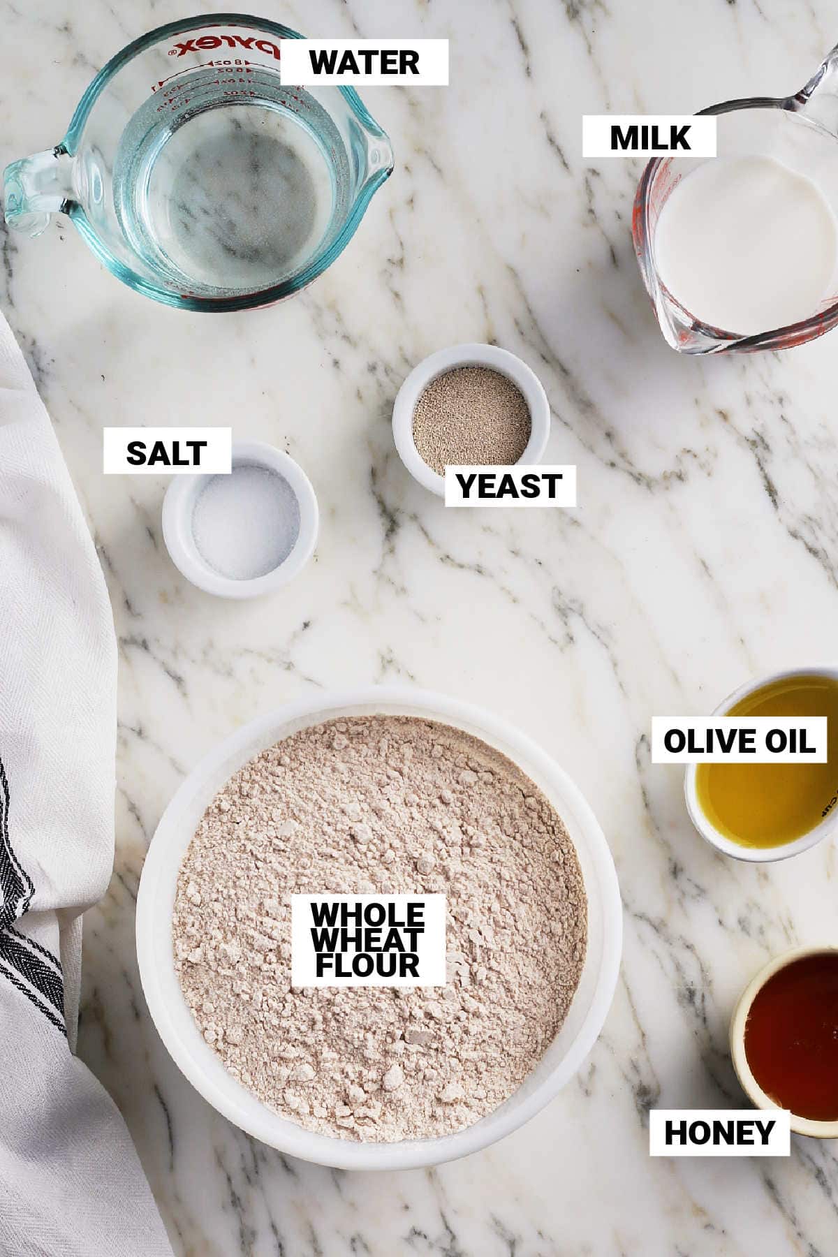 whole wheat flour, honey, olive oil, salt, yeast, milk, and water mise en place to make honey wheat bread