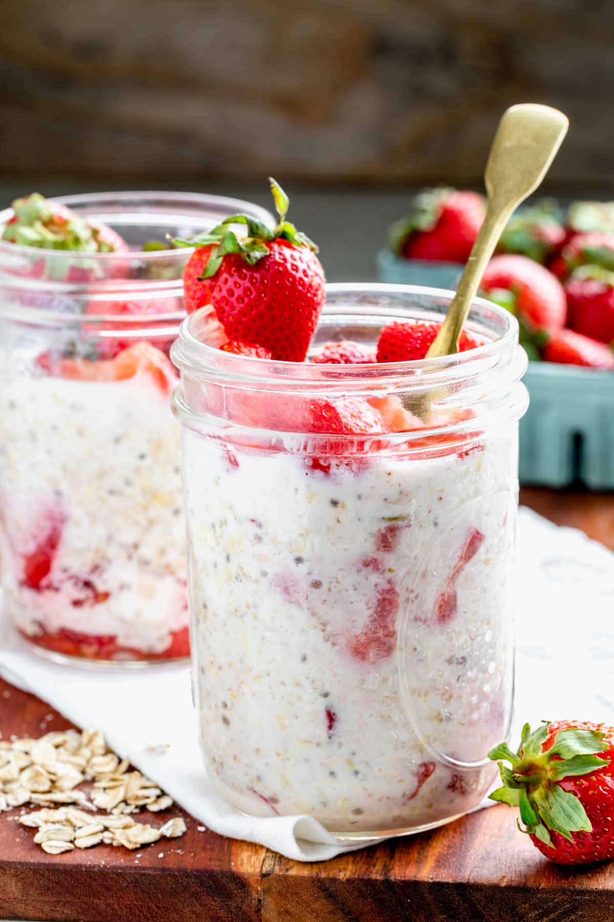 strawberry overnight oats in mason jars with strawberries on top for a garnish