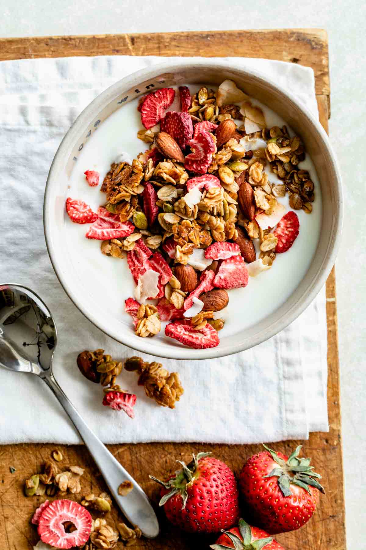 an off-white bowl full of milk and topped with homemade berry granola