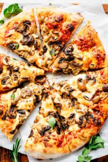 overhead p،to of sliced pizza with mushrooms on cutting board