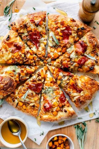 Butternut Squash Pizza served on a wooden board with plenty of sides around it