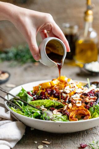 pouring balsamic maple salad dressing over salad