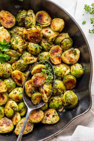 sauteed brussels sprouts in a skillet with herbs and balsamic