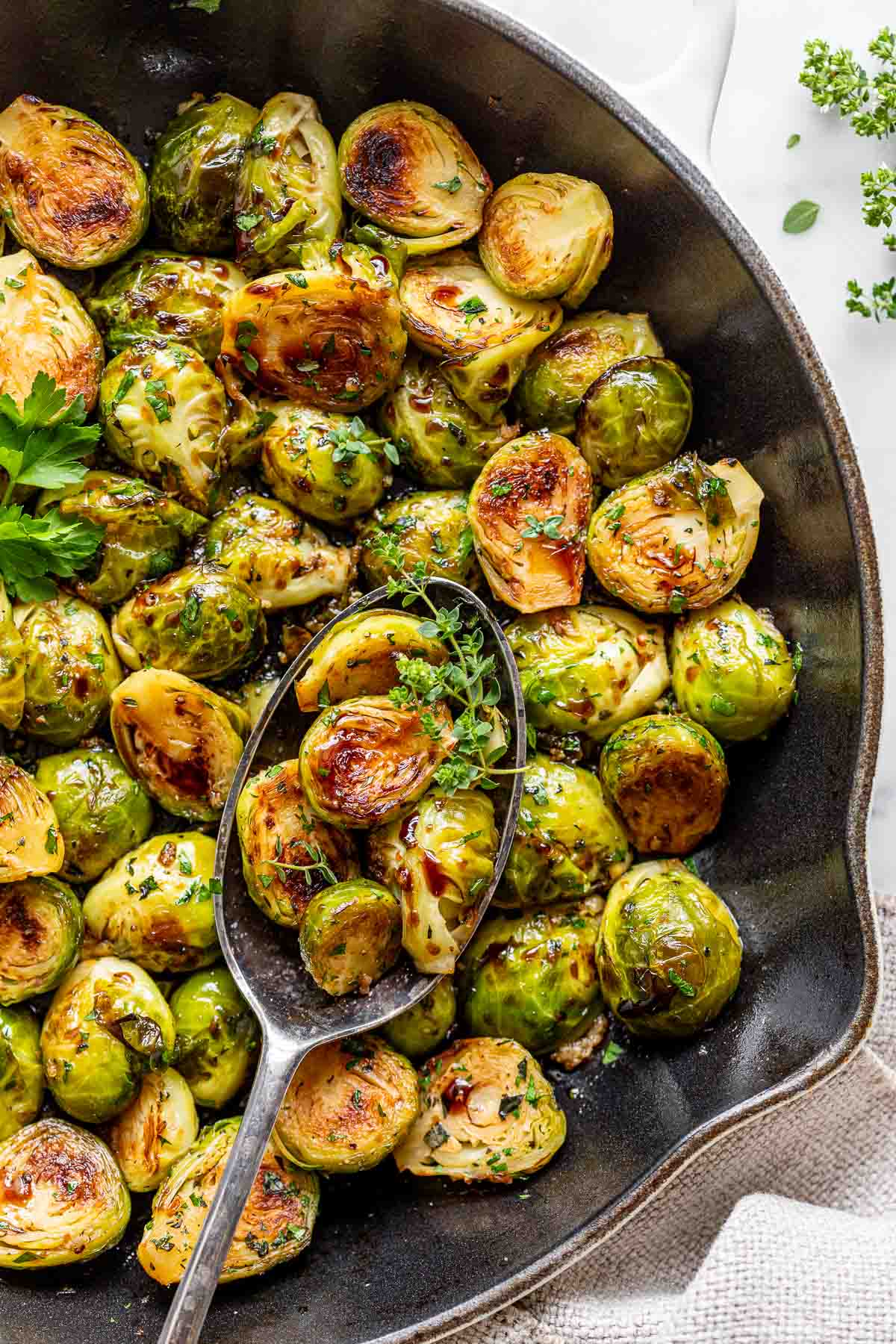 sauteed brussels sprouts browned and tossed with herbs and balsamic in a cast iron skillet