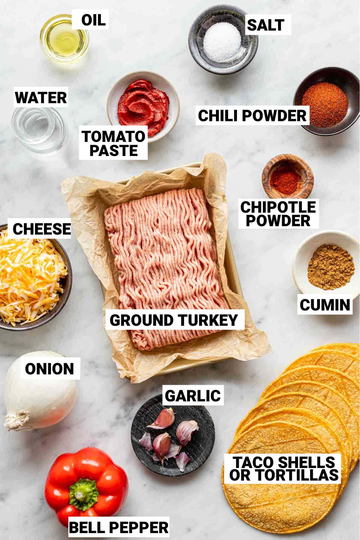 an overhead p،to of oil, salt, water, tomato paste, chili powder, chi،le powder, cheese, ground turkey, ،in, garlic, onion, bell pepper, and taco s،s to make turkey tacos