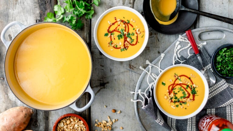 My easy but super delicious Sweet Potato Peanut Soup in a pot with two bowls dished out