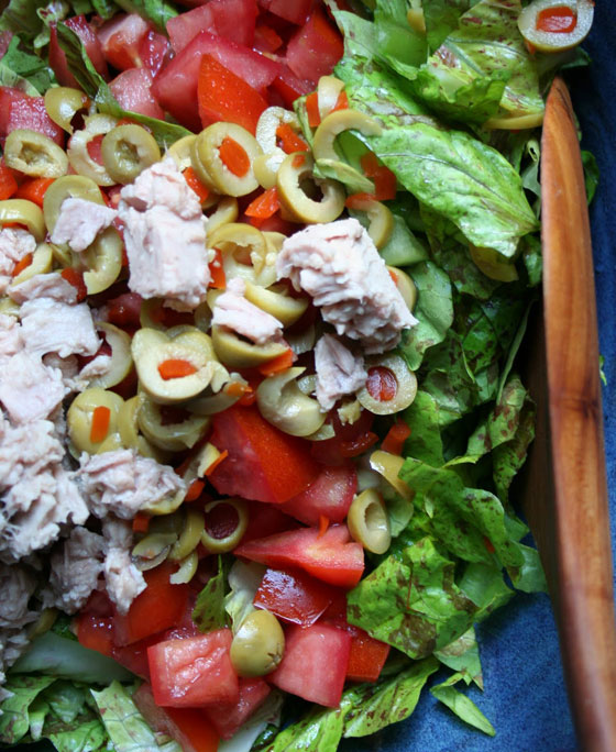 A bowl of salad, with Tomato and Lettuce and olives and tuna